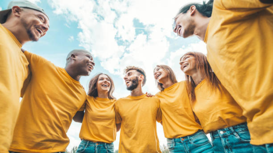 gruppo di ragazzi sorridenti che indossano una maglietta gialla e sono abbracciati