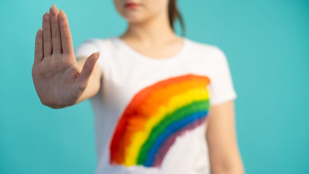 ragazza con maglietta rainbow che ferma il bullismo con la mano