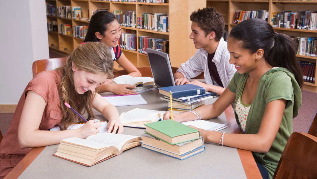 Giovani che studiano su un tavolo con libri e computer
