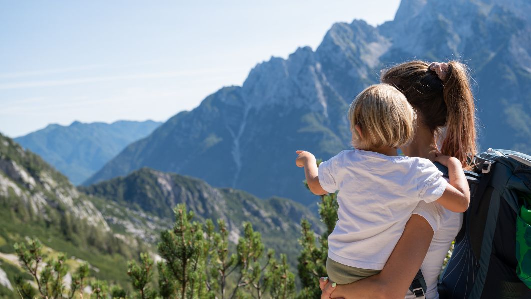 ragazza con bimba in braccio davanti a panorama montano