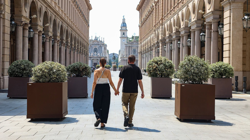 Due persone viste di spalle camminano in via Roma