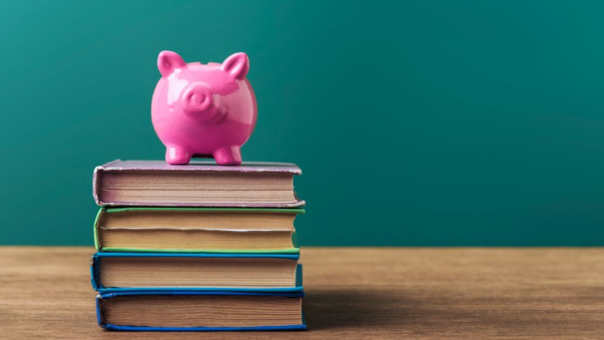 Salvadanaio rosa poggiato su una pila di libri
