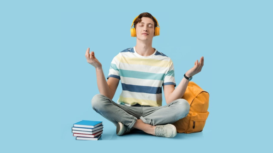 ragazzo seduto che medita con le cuffie per ascoltare la musica, vicino ha uno zaino e dei libri