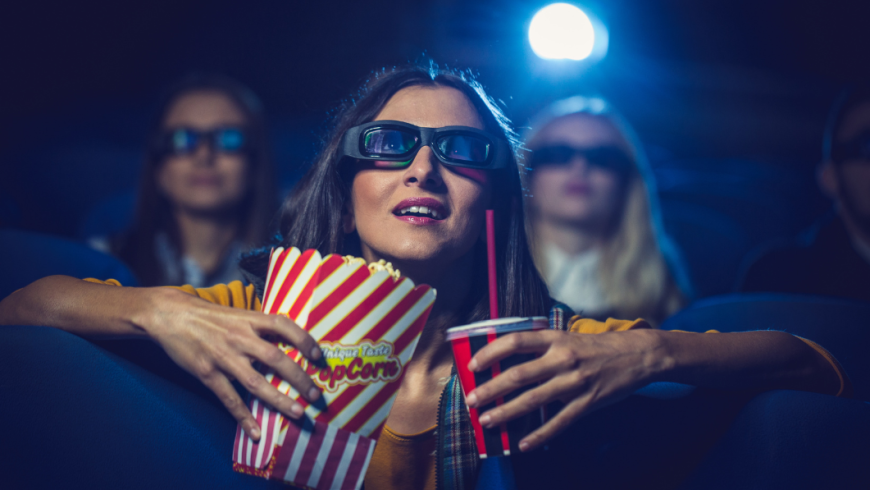 ragazza con occhiali per visione in 3d con in mano pop corn e bibita in un bicchiere con cannuccia