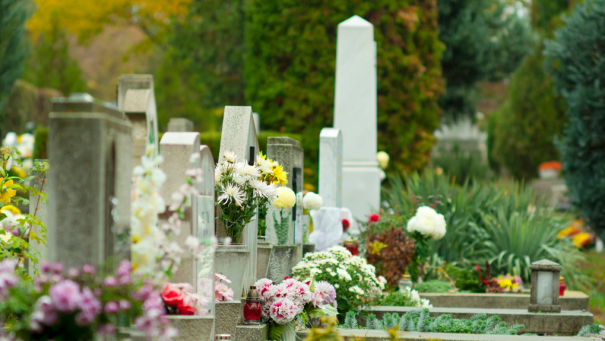 una serie di lapidi e tombe in un cimitero, decorate con fiori colorati e vasi