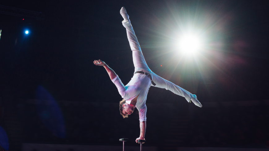 Ragazzo vestito di bianco che si tiene in equilibrio su una mano