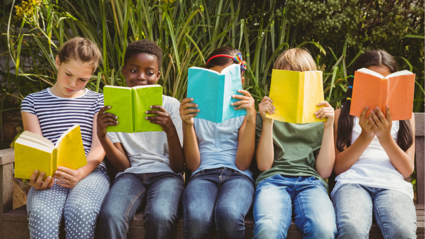 5 bambini seduti su una panchina che stanno leggendo un libro