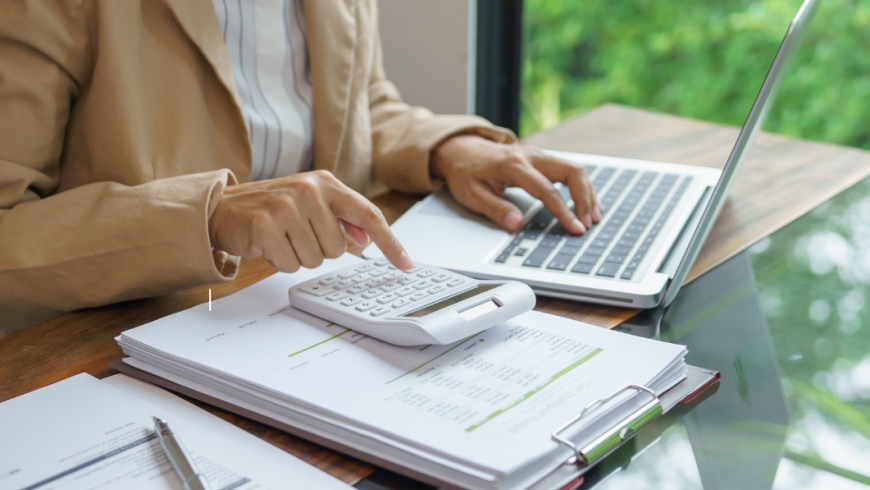 persona che fa calcoli con una calcolatrice e ha computer vicino