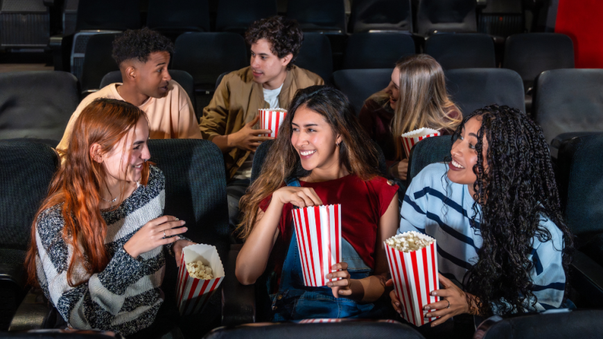 ragazzi e ragazze al cinema con pop corn che parlano