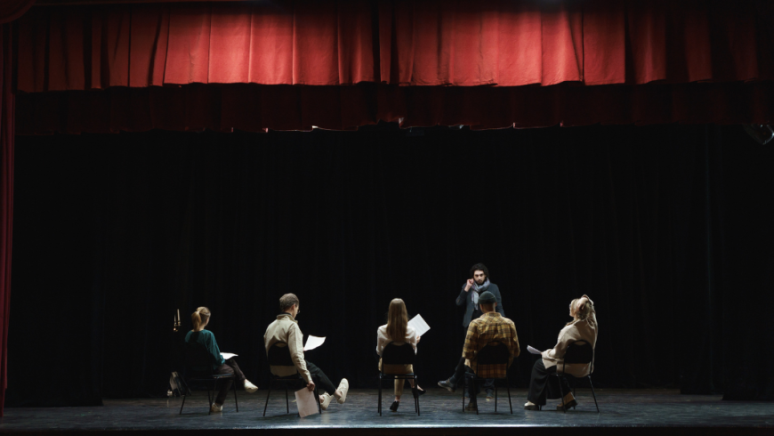 gruppo di attori seduti su un palco teatrale