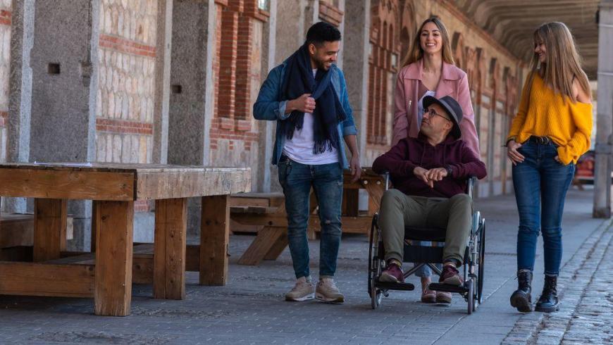 quattro persone che fanno una passeggiata tra cui un signore in sedia a rotelle