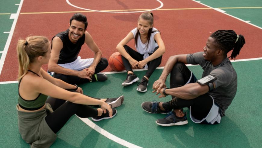 gruppo di ragazze e ragazzi seduti su un campo sportivo all'aperto