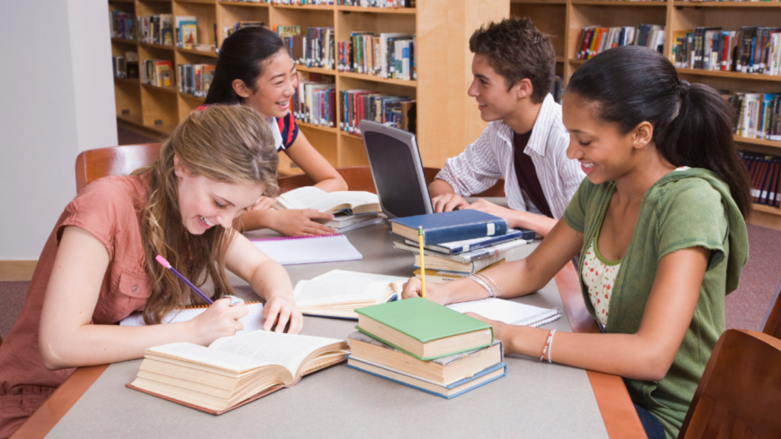 Giovani che studiano su un tavolo con libri e computer