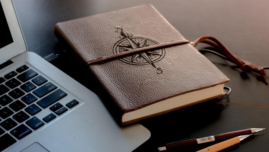 diario rilegato in pelle e PC sulla scrivania