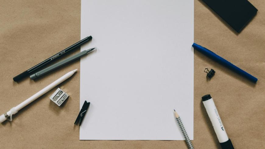 Scrivania con foglio bianco e penne