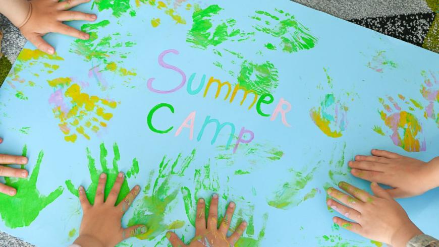 mani su una mappa con scritta summer camp
