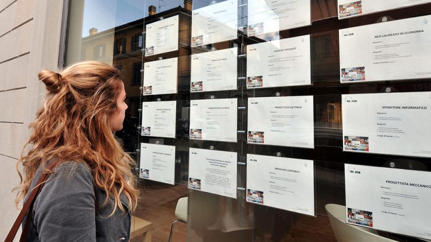 ragazza che legge annunci lavoro in vetrina di agenzia