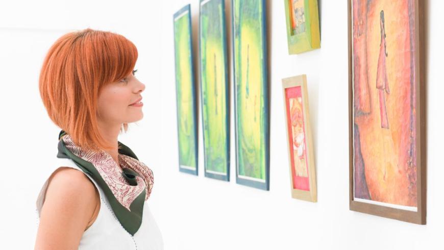 ragazza che guarda una fila di quadri