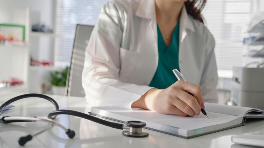 Medico nel suo studio scrive su un'agenda