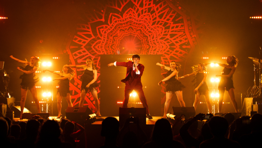 Palco con ragazzo che canta e ballerine 