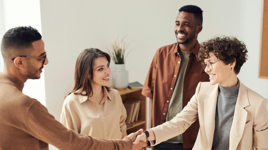 gruppo di quattro persone tra le quali due si stringono la mano