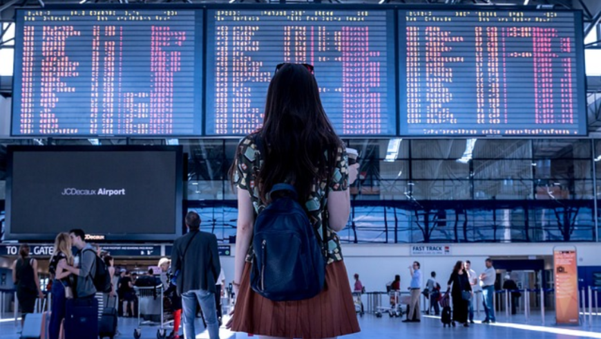 ragazza davanti a tabellone partenze aeroporto