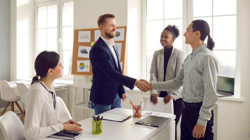persone che si stringono la mano davanti ad una scrivania di un ufficio