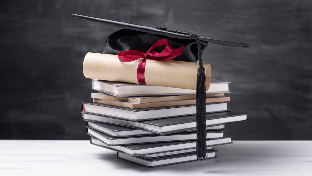 Pila di tesi di laurea con diploma e cappello